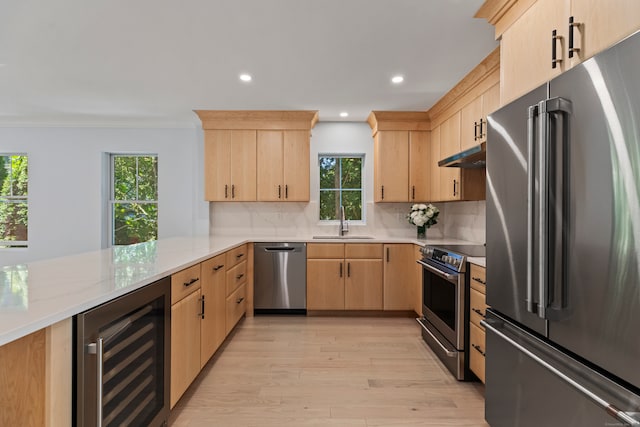 kitchen with wine cooler, plenty of natural light, kitchen peninsula, appliances with stainless steel finishes, and light brown cabinetry