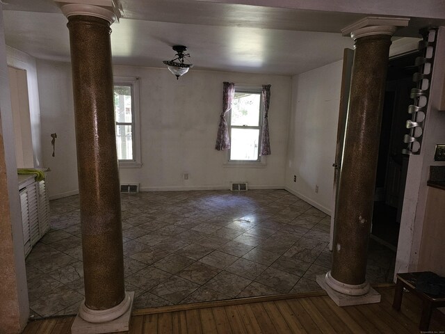 spare room featuring hardwood / wood-style flooring, ornate columns, and a healthy amount of sunlight