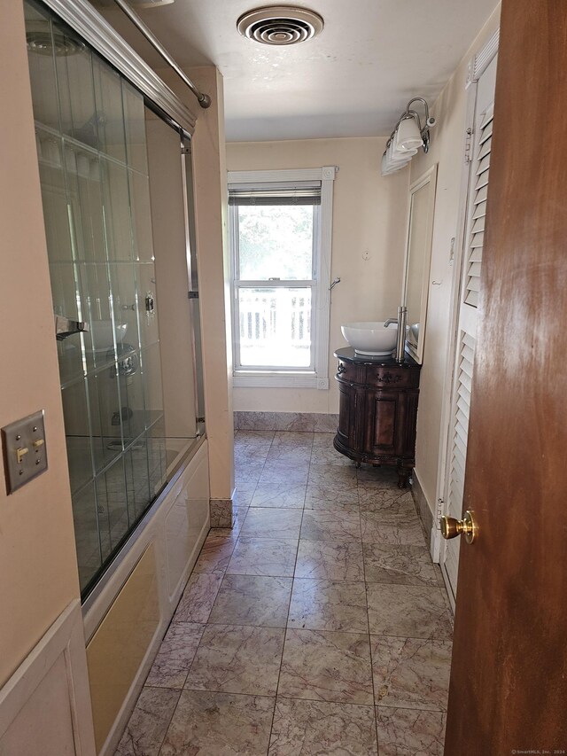 bathroom with combined bath / shower with glass door and vanity