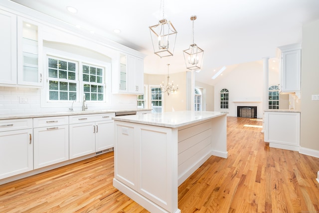 kitchen with a kitchen island, backsplash, white cabinets, and decorative light fixtures