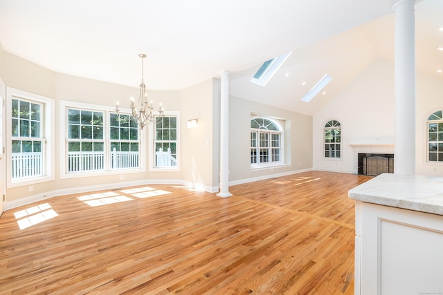 unfurnished living room featuring high vaulted ceiling, light hardwood / wood-style flooring, and a notable chandelier