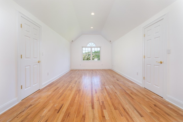 spare room featuring lofted ceiling and light hardwood / wood-style flooring