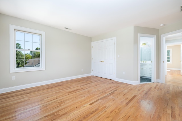 unfurnished bedroom with light wood-type flooring, a closet, and connected bathroom