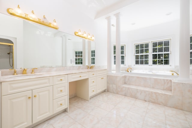 bathroom with tiled bath, vanity, and decorative columns