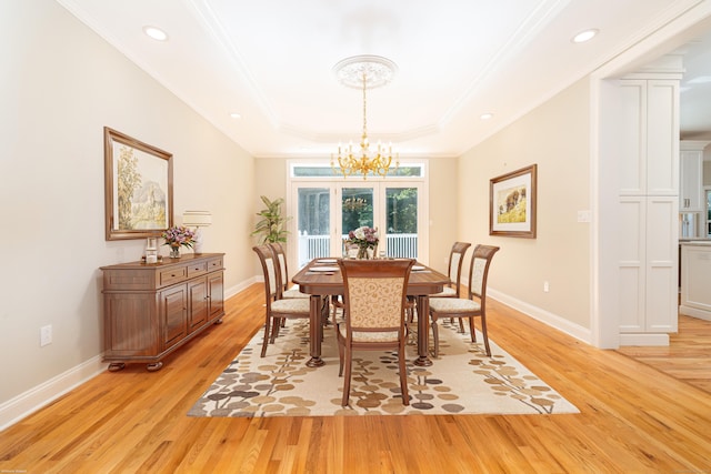 dining space featuring a chandelier, light hardwood / wood-style flooring, a raised ceiling, and ornamental molding