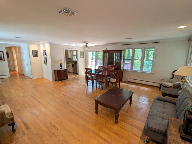 living room with light hardwood / wood-style flooring, baseboard heating, and ceiling fan