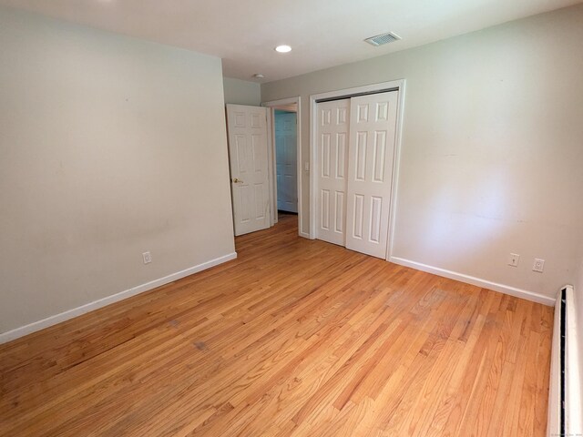 empty room with a baseboard heating unit and light hardwood / wood-style floors