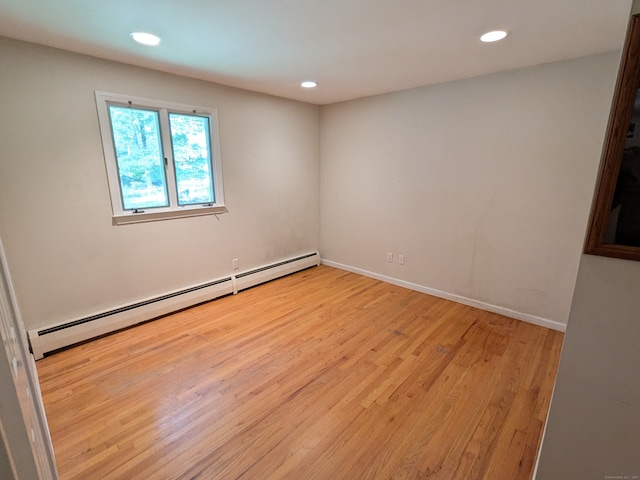 empty room with a baseboard heating unit and light hardwood / wood-style flooring