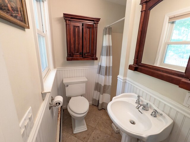 bathroom featuring tile patterned flooring, a shower with shower curtain, toilet, and sink