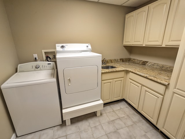 clothes washing area with washer and dryer, cabinets, sink, and light tile patterned floors