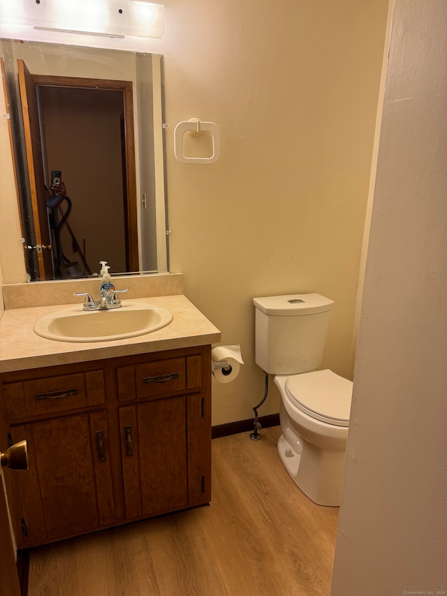 bathroom with hardwood / wood-style floors, vanity, and toilet