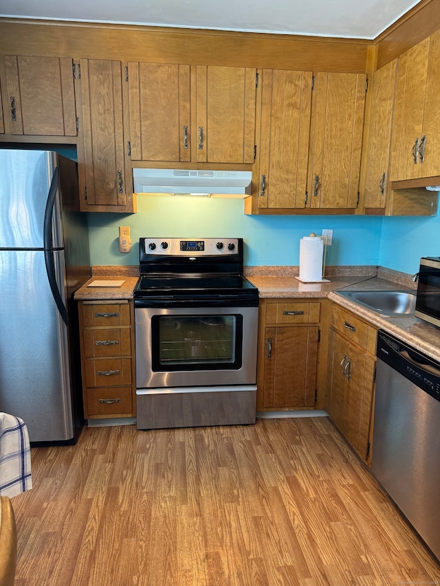 kitchen with stainless steel appliances, light hardwood / wood-style flooring, and sink