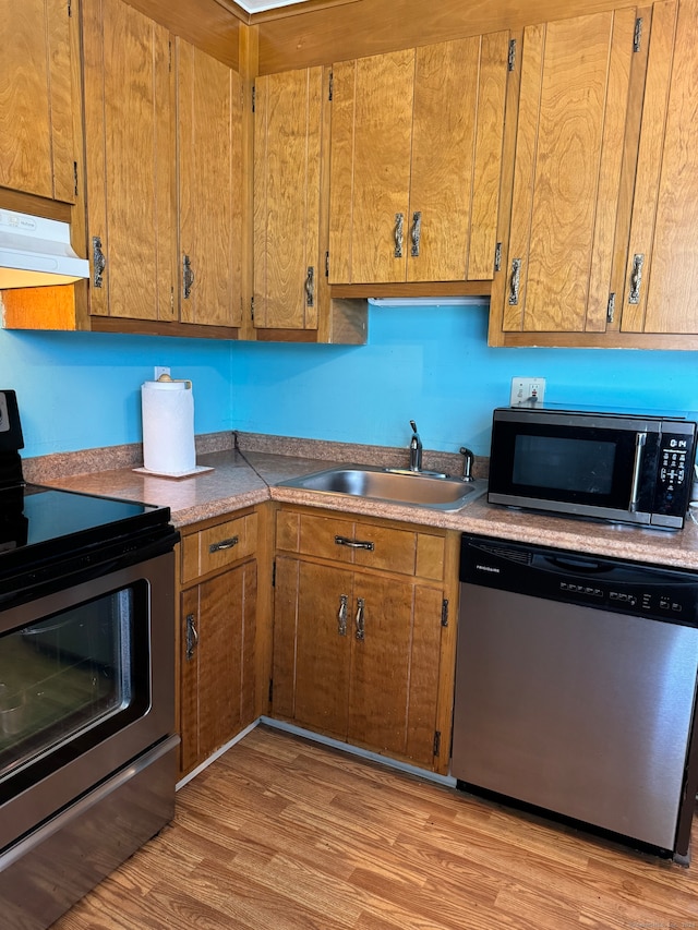 kitchen with sink, stainless steel appliances, and light hardwood / wood-style flooring