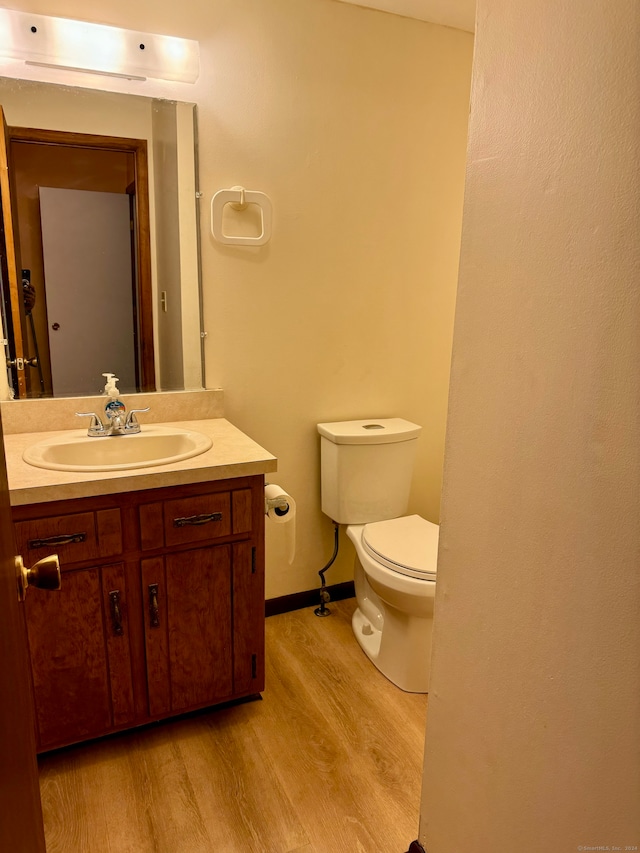 bathroom with wood-type flooring, vanity, and toilet