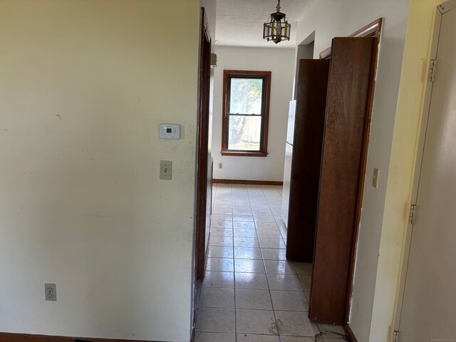 corridor with a textured ceiling and light tile patterned flooring