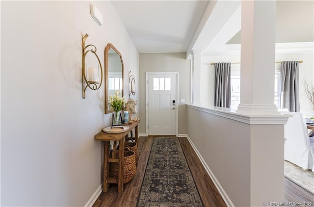 doorway to outside with dark wood-style flooring, baseboards, and decorative columns