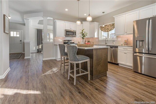 kitchen with a kitchen island, stainless steel appliances, white cabinetry, and ornate columns