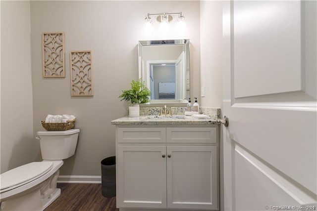 bathroom featuring vanity, toilet, wood finished floors, and baseboards