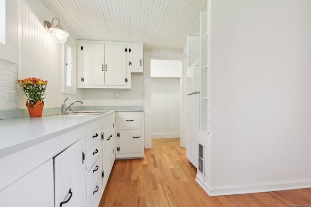 kitchen with light wood-type flooring, white cabinets, and sink