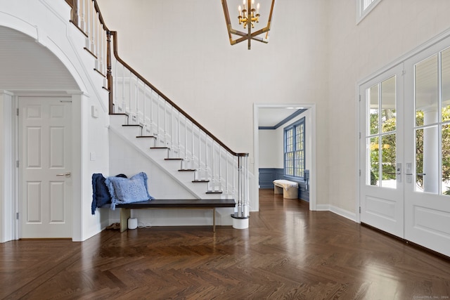 entryway with a chandelier, dark parquet flooring, a towering ceiling, and french doors