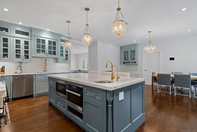 kitchen featuring pendant lighting, sink, an island with sink, and stainless steel appliances