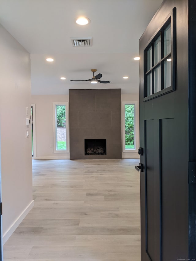 living room featuring light hardwood / wood-style floors, a healthy amount of sunlight, a fireplace, and ceiling fan