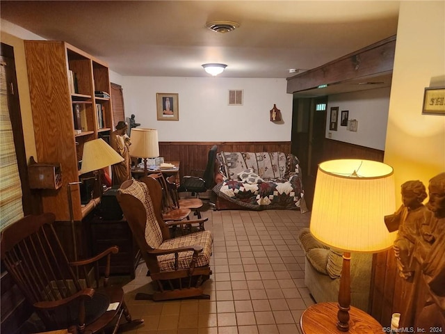 sitting room featuring wooden walls and light tile patterned flooring