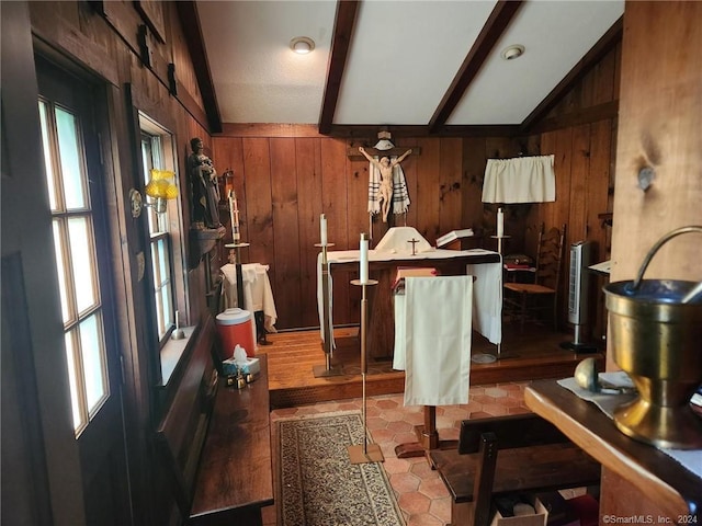 interior space with lofted ceiling with beams, wood walls, and a wealth of natural light