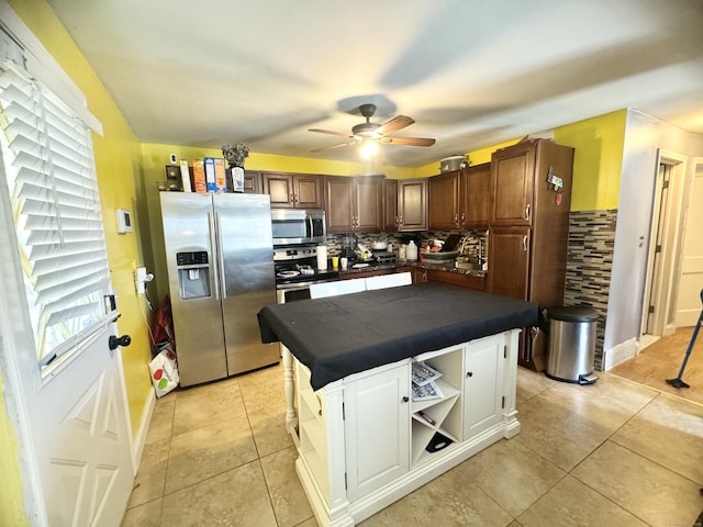 kitchen with light tile patterned flooring, stainless steel appliances, a center island, and tasteful backsplash