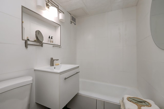 full bathroom with vanity, tile walls, toilet, and shower / washtub combination