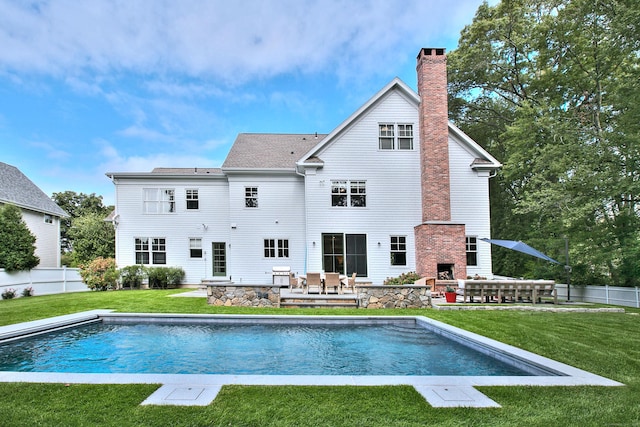 back of house featuring a fenced in pool, fence, a chimney, an outdoor stone fireplace, and a yard