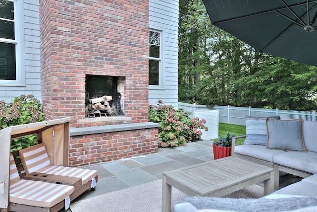 view of patio / terrace with an outdoor living space with a fireplace and fence