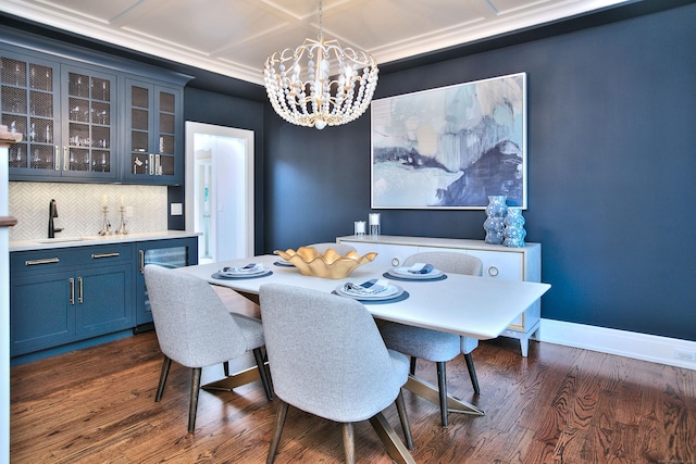 dining room featuring indoor wet bar, baseboards, dark wood-type flooring, and an inviting chandelier