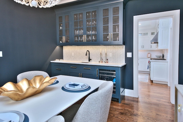 dining room with indoor wet bar, beverage cooler, dark wood finished floors, and a chandelier