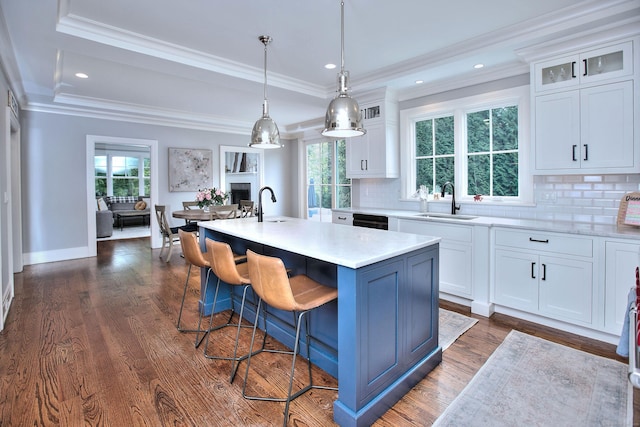 kitchen with ornamental molding, a sink, light countertops, dark wood-type flooring, and white cabinetry