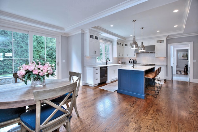 kitchen with crown molding, dishwasher, light countertops, a raised ceiling, and dark wood-style flooring