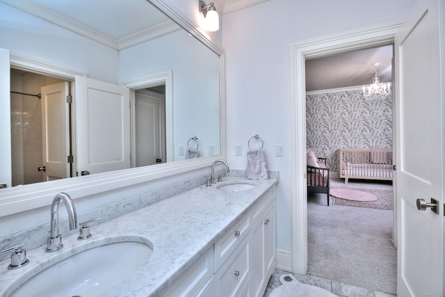 ensuite bathroom featuring a sink, an inviting chandelier, ornamental molding, and double vanity