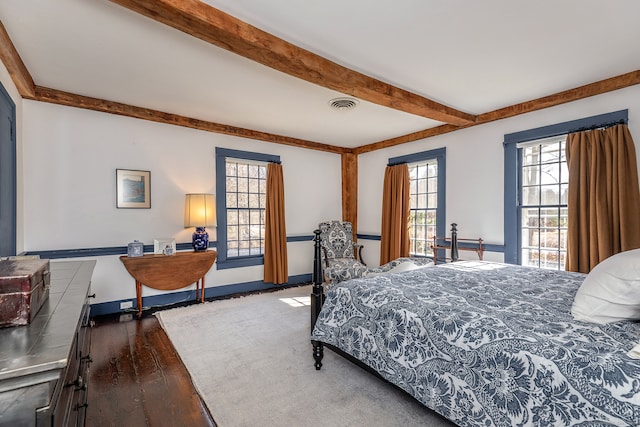 bedroom featuring dark hardwood / wood-style flooring and beam ceiling