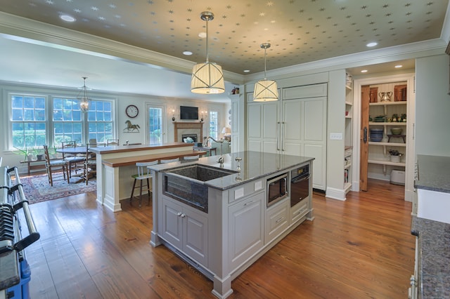 kitchen with white cabinets, dark hardwood / wood-style flooring, pendant lighting, a center island, and ornamental molding