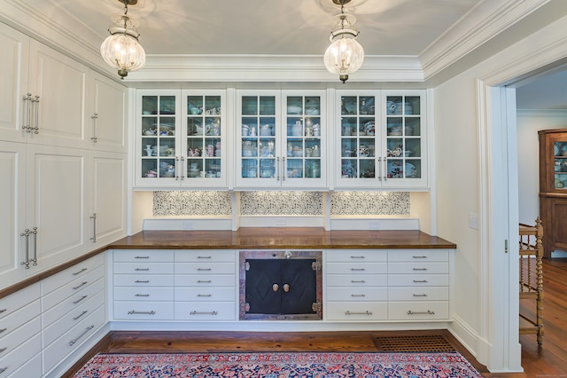 kitchen featuring crown molding, white cabinets, hanging light fixtures, and dark hardwood / wood-style flooring