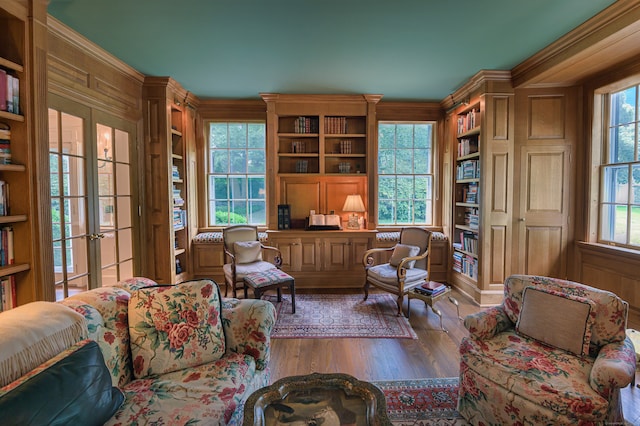 living area featuring crown molding, wood-type flooring, built in shelves, and wood walls