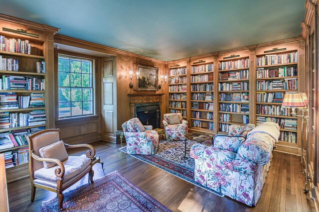 sitting room with wood finished floors, a fireplace, bookshelves, and built in features