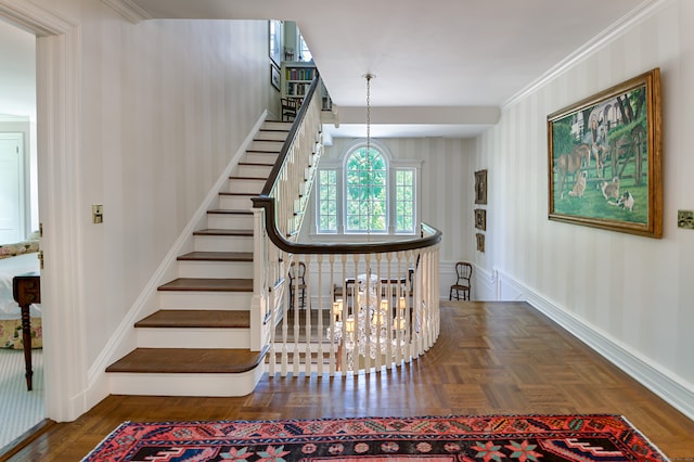 stairway featuring an inviting chandelier, crown molding, and parquet floors