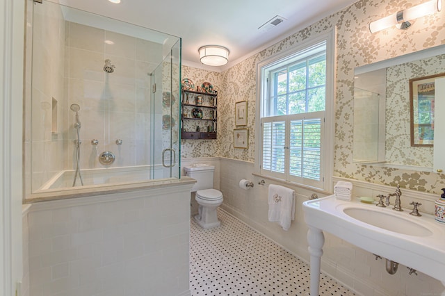 bathroom featuring wallpapered walls, a stall shower, toilet, visible vents, and a sink