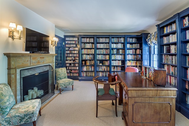 carpeted office space with a fireplace and wall of books
