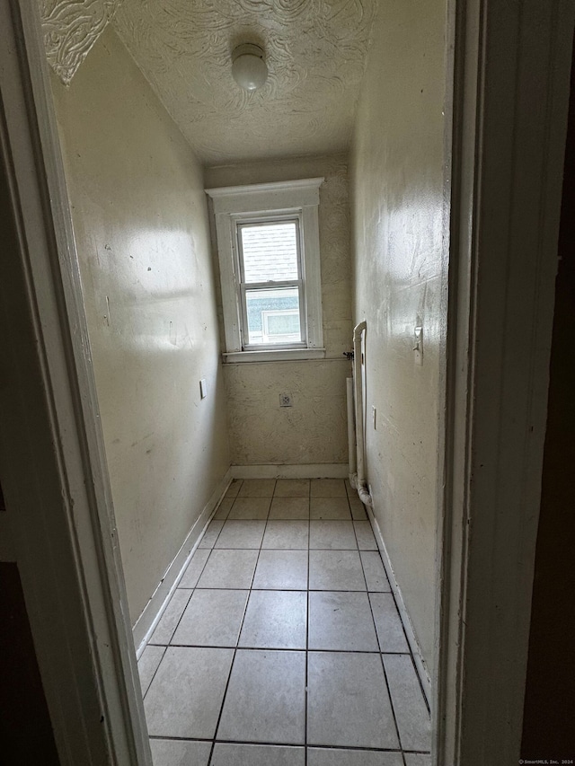 corridor featuring a textured ceiling and light tile patterned flooring