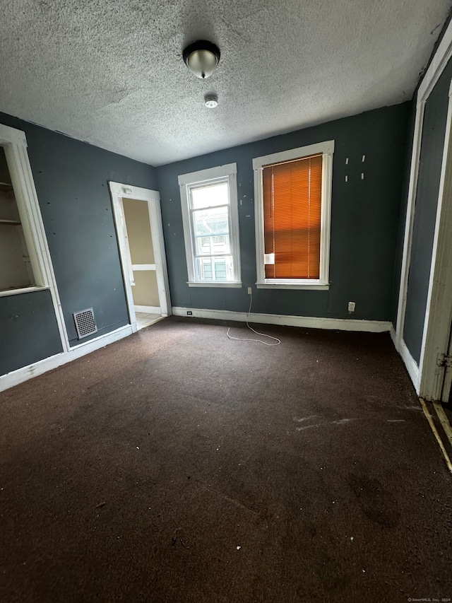 carpeted empty room featuring a textured ceiling