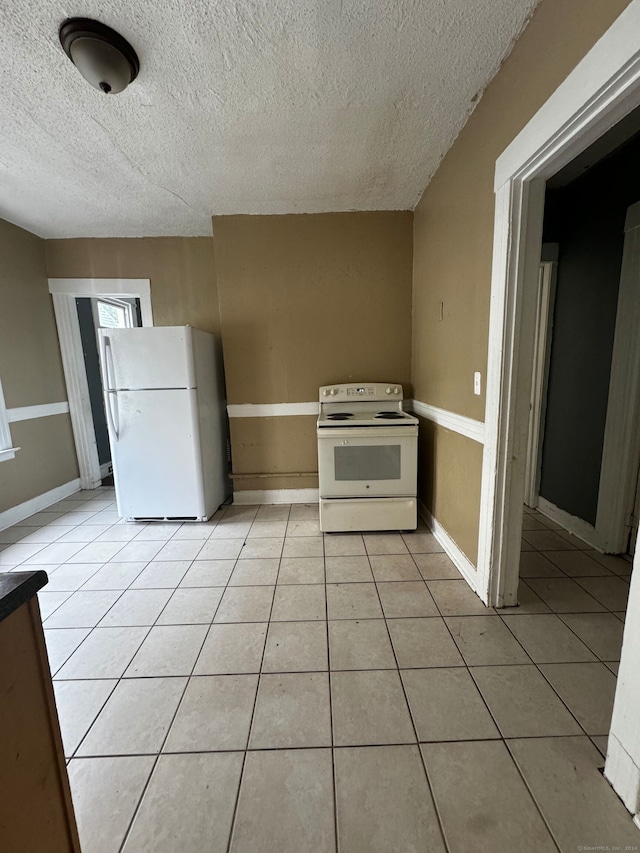 kitchen with white appliances, light tile patterned floors, and a textured ceiling