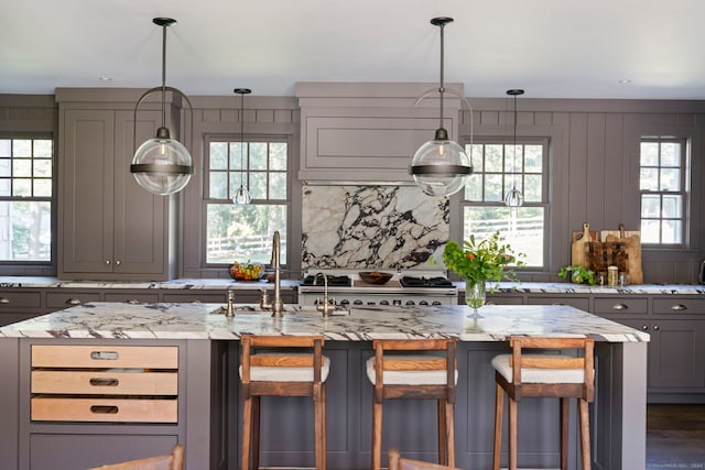 kitchen featuring a healthy amount of sunlight, light stone countertops, a kitchen breakfast bar, and gray cabinets