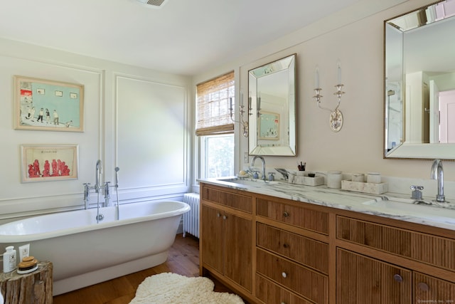 bathroom featuring vanity, radiator heating unit, wood-type flooring, and a washtub